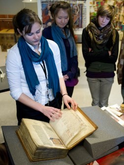 Jongeren maken in de Openbare Bibliotheek Brugge kennis met een handschrift | © Vlaamse Erfgoedbibliotheek - Foto: Stefan Tavernier Jonge vrouw bladerd door handschrift