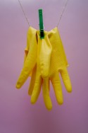Twee gele schoonmaakhandschoenen aan een waslijn opgehangen