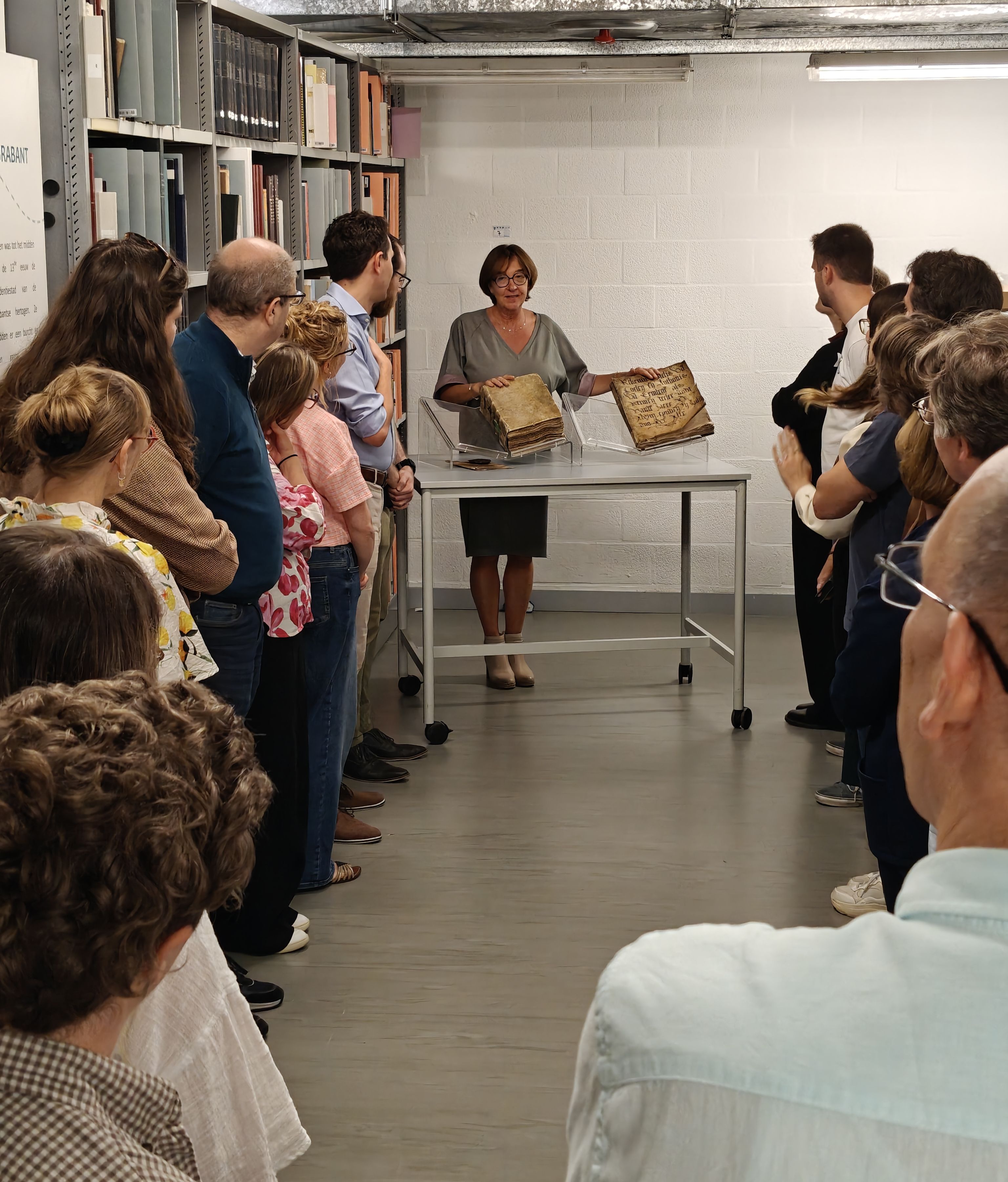 Een groep mensen bekijken een presentatie van twee boeken door een vrouw